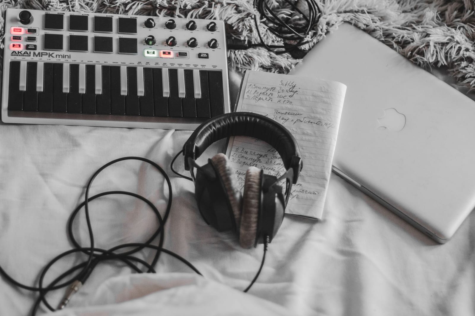 Laptop, headphones and a MIDI keyboard on a desk, ready for making a music video