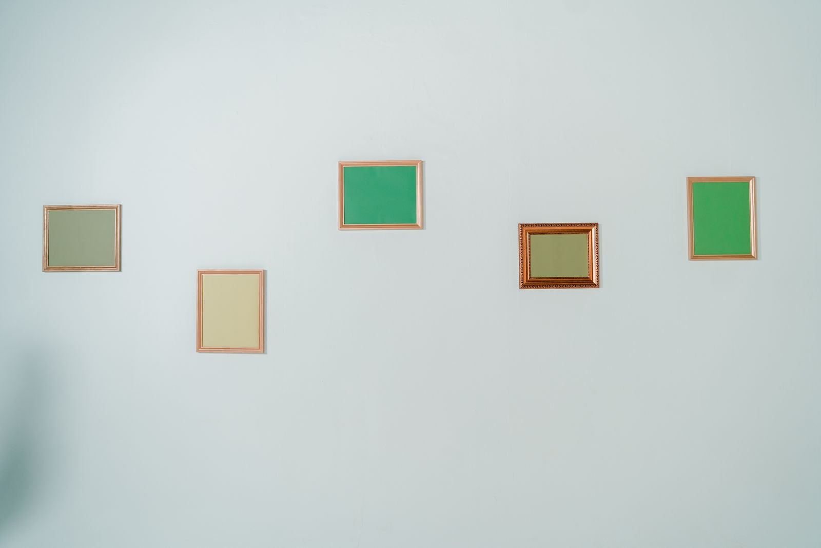 Several small empty frames hanging on a pale wall