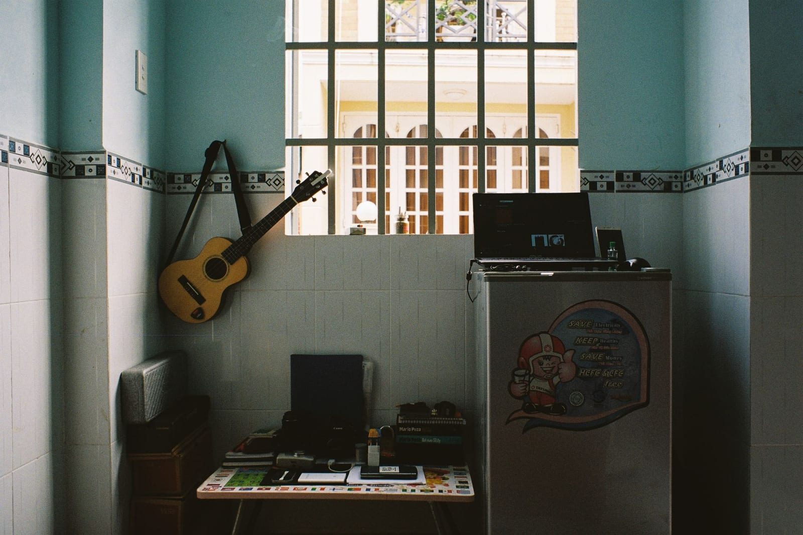 A home music workspace with a laptop and a guitar on the wall