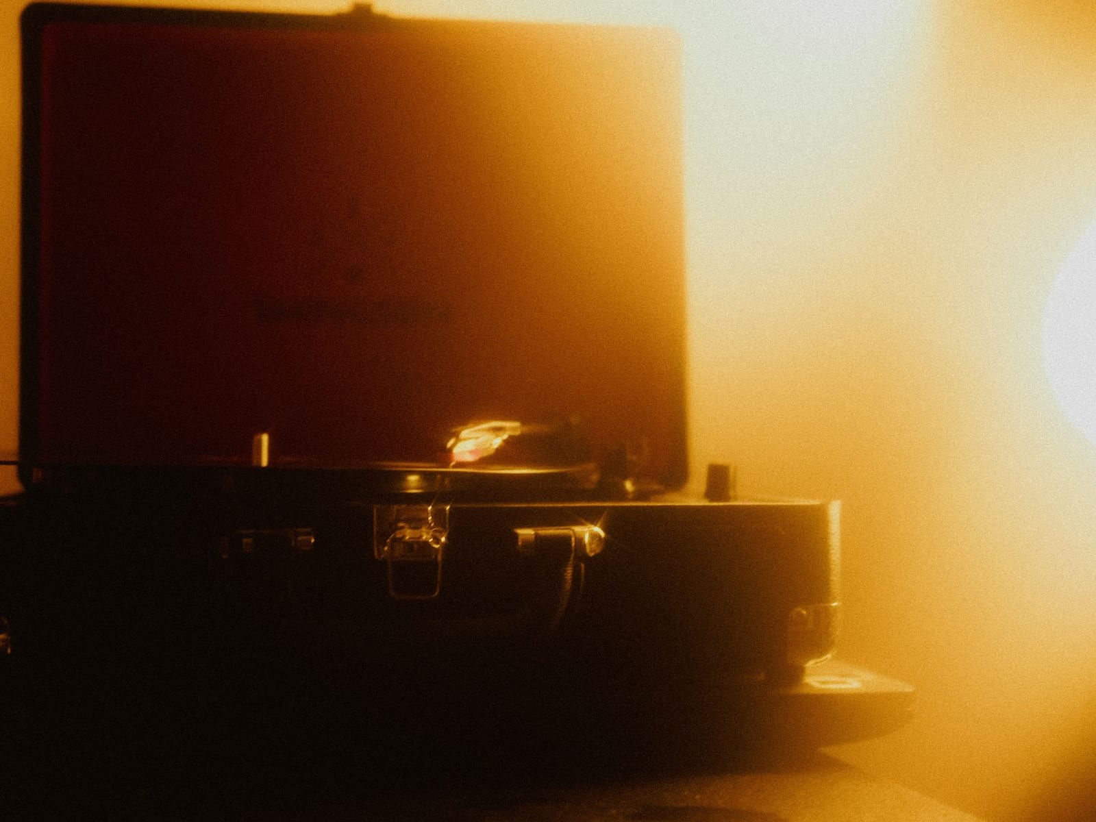 A turntable playing a vinyl record in warm orange light
