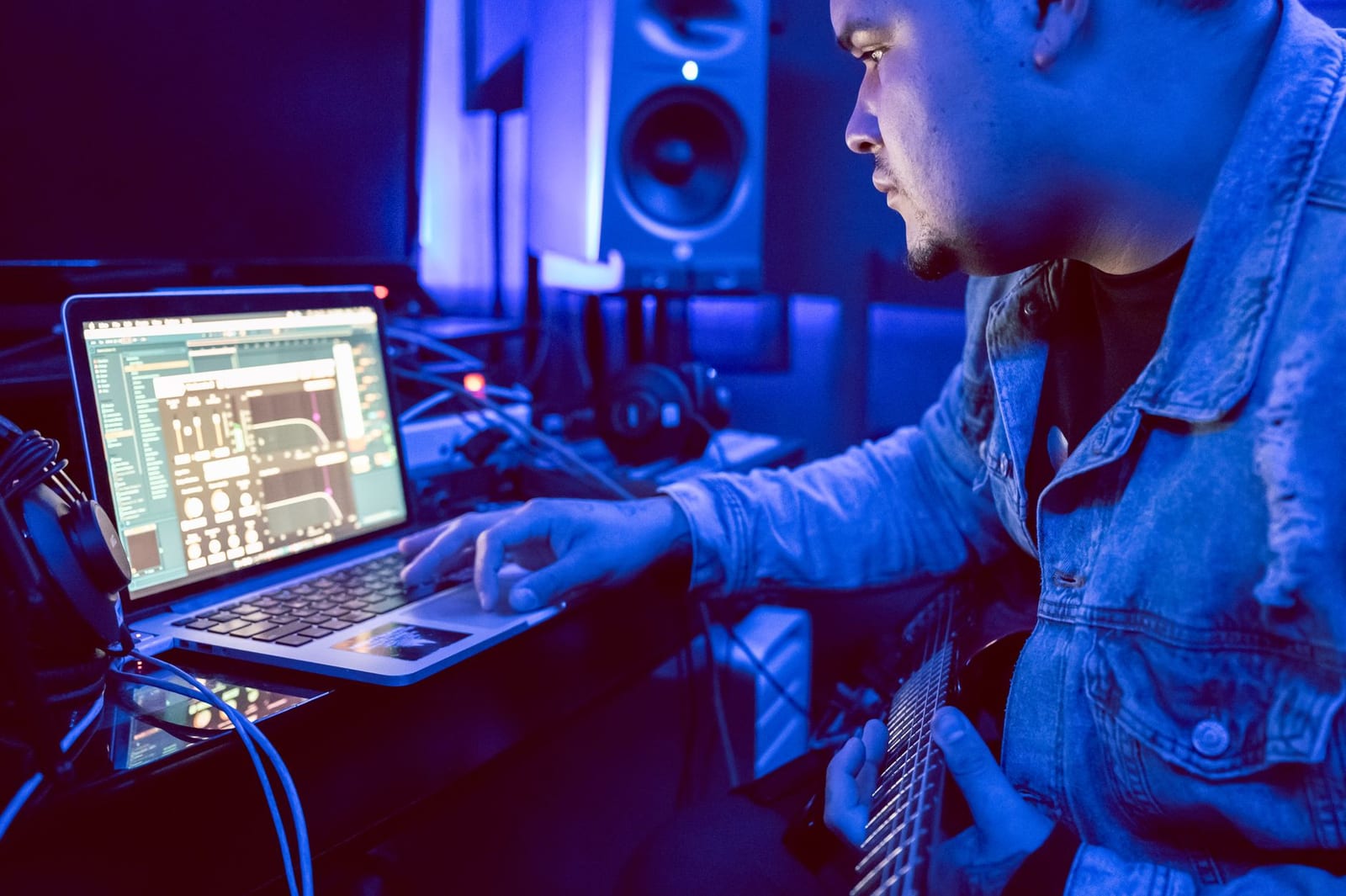 Young musician using a laptop for music production in a studio