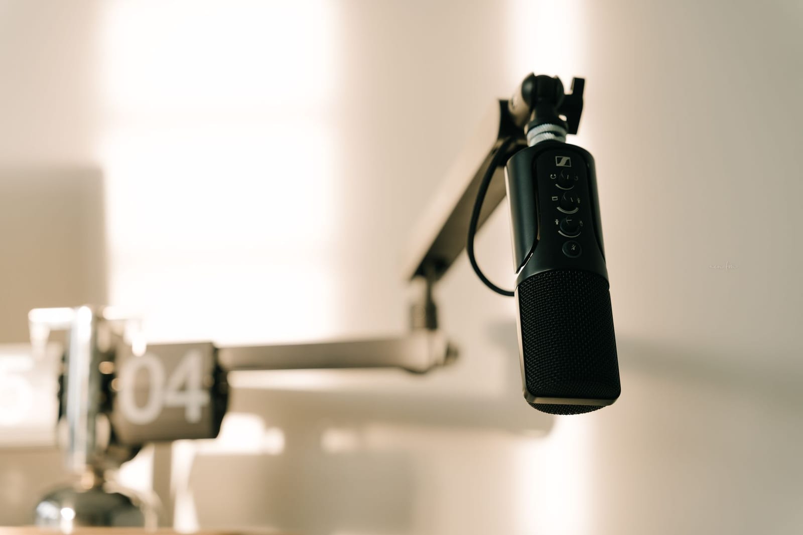 A professional microphone on a boom arm in a minimal studio