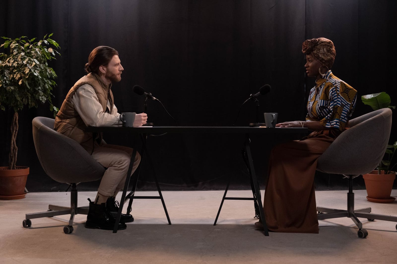 Two people talking at microphones in a podcast studio