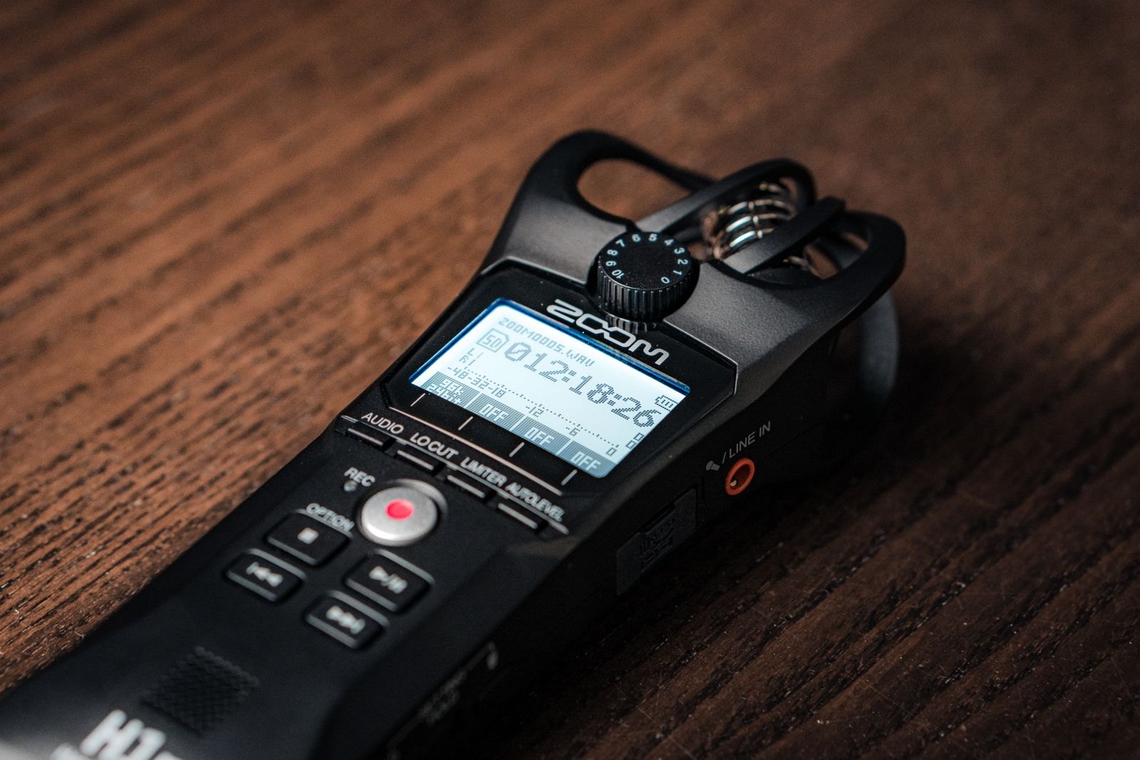 A small digital audio recorder lying on a wooden table