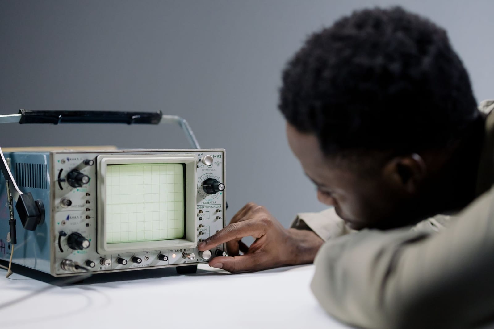 A person adjusting a vintage oscilloscope