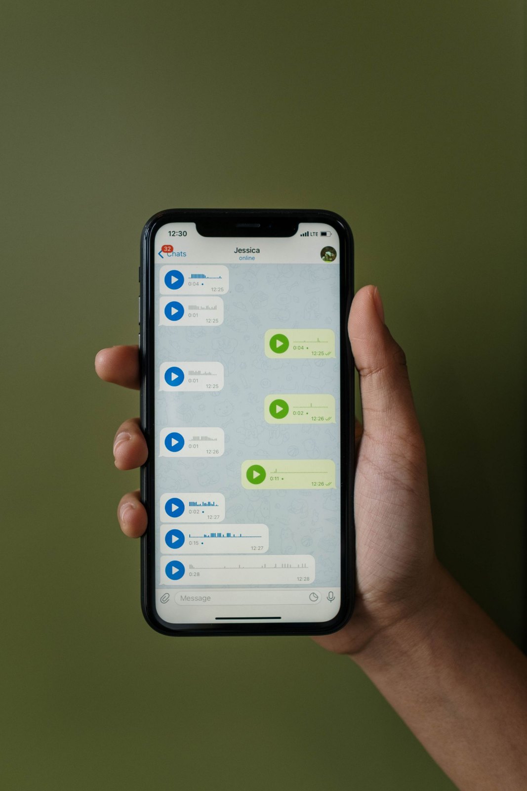A hand holding a smartphone showing a chat with several voice messages